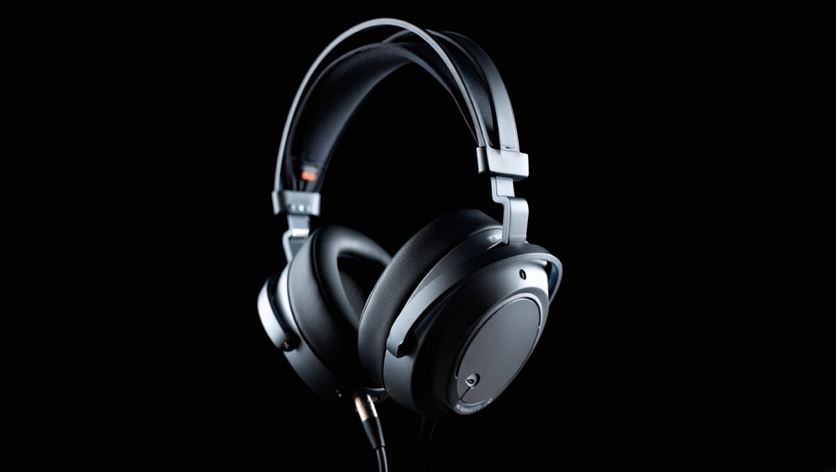Black over-ear headphones with mesh speaker grills resting on a colorful book with blue, yellow, red, and gray sections.