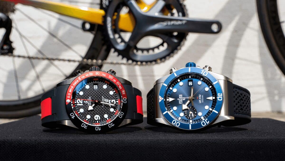 Black chronograph wristwatch with fabric strap worn on a wrist gripping a bicycle handlebar wrapped in black tape.