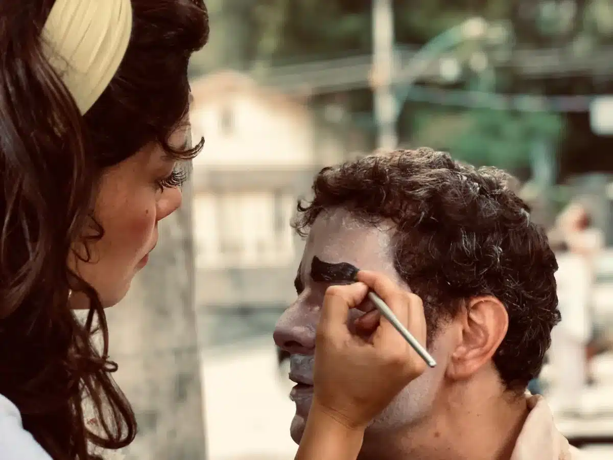 A makeup artist applying age-enhancing makeup and prosthetics to an actor's face