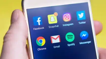 Hands holding a smartphone displaying social media reactions and debate comments on screen
