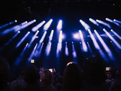 Empty concert stage with microphone stand under soft spotlight, symbolizing a performer's transition