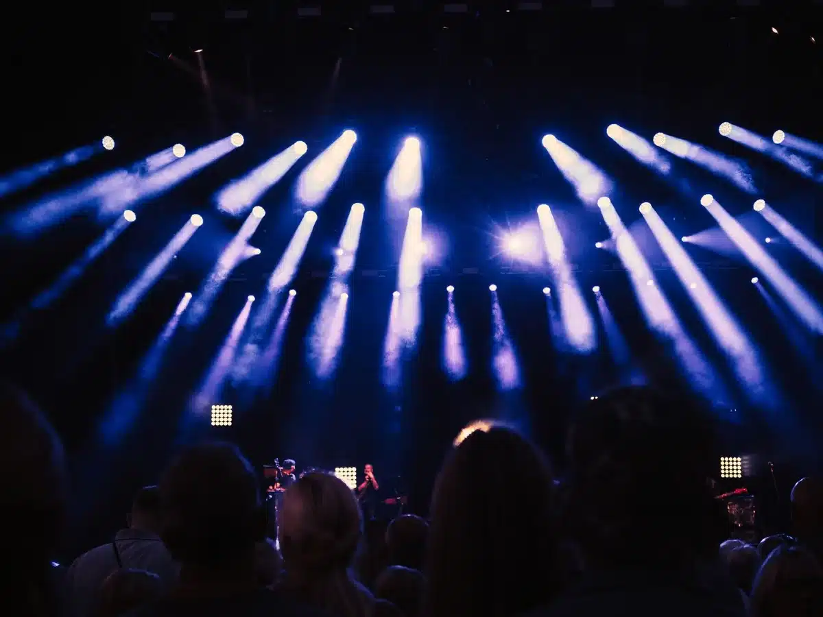 Empty concert stage with microphone stand under soft spotlight, symbolizing a performer's transition