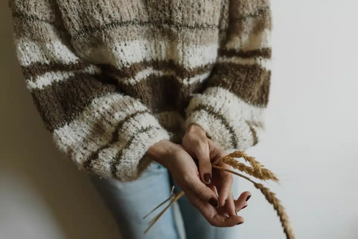 Knit ballet flats paired with denim and oversized sweater on neutral surface