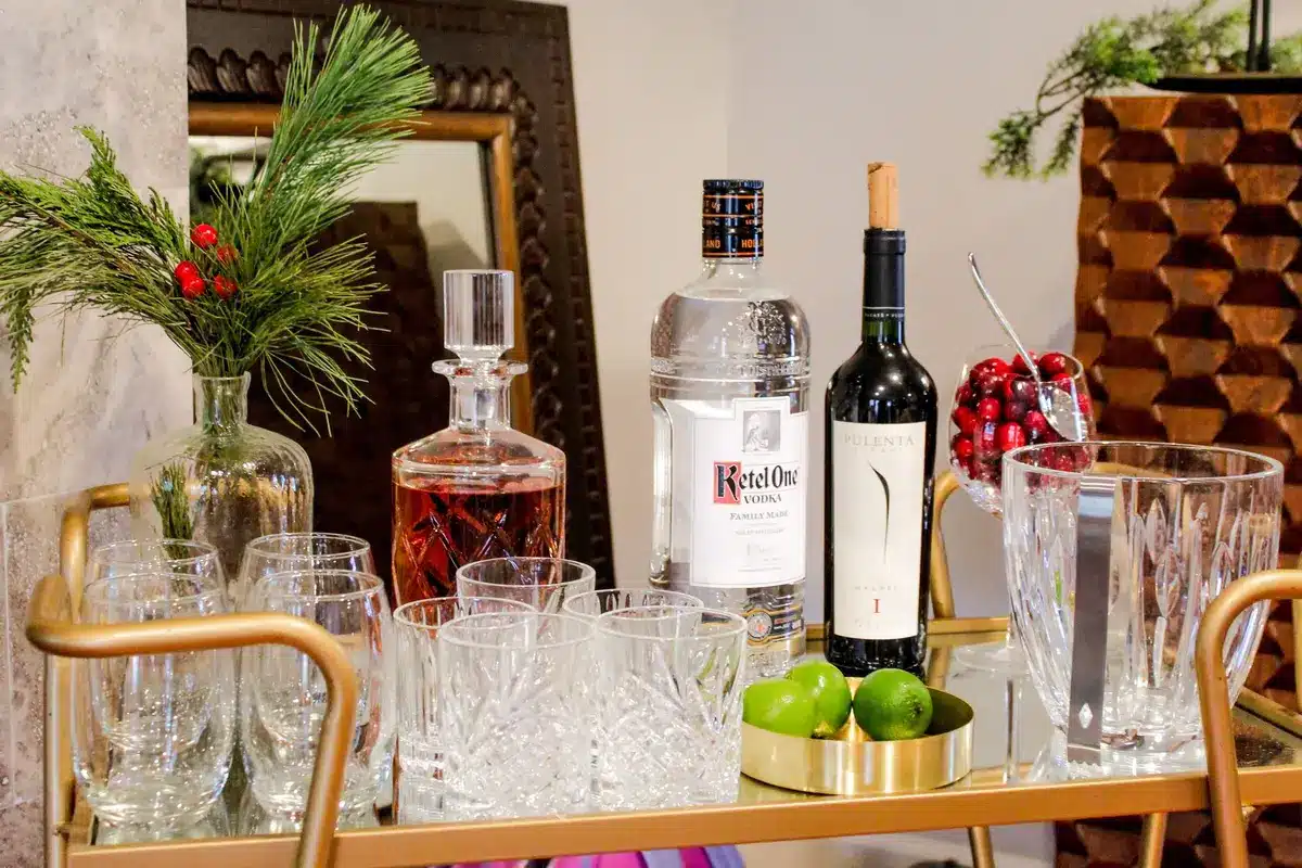 Organized home bar shelf with various bottles, glasses, citrus slices, and bar tools