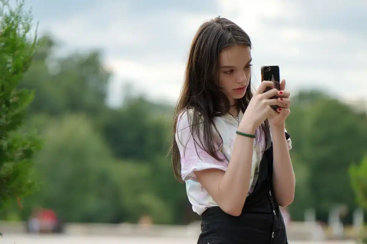 Young woman sitting on a bed holding a smartphone, suggesting online content creation