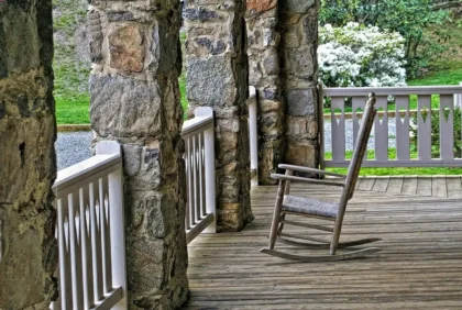 Silhouette of an acoustic guitar on a weathered porch with Appalachian woods beyond