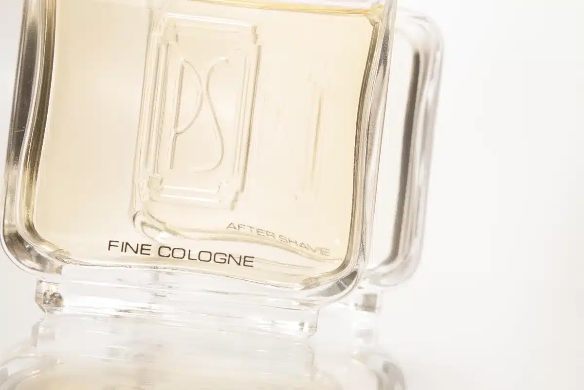 Two perfume bottles beside herbs and charcoal representing contrast in fragrance