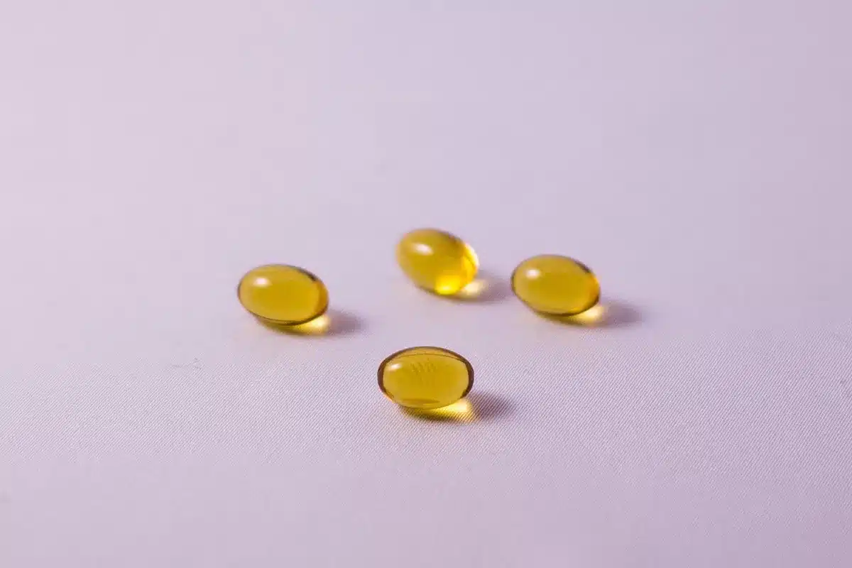 Close-up of omega-3 softgels spilling from a bottle, highlighting capsules per serving