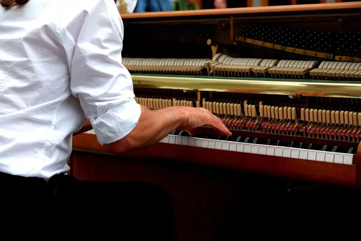 Pianist practising at an upright piano in a dim, cold room