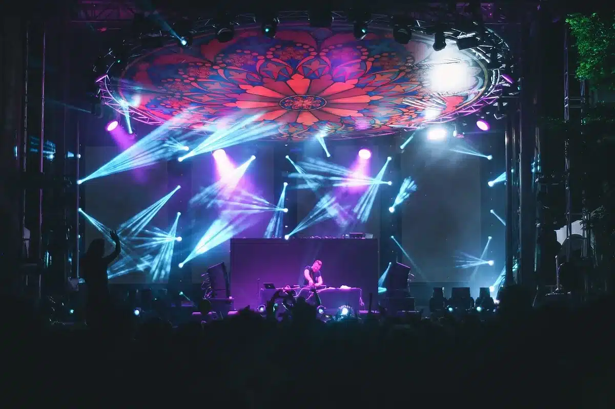 Crowd at a concert mid-mosh with raised hands and energetic lighting
