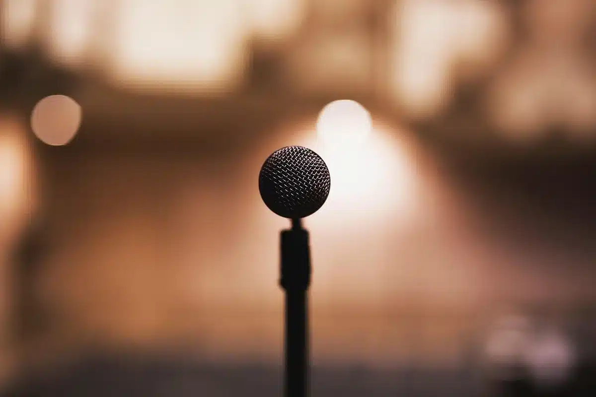 Comedian on stage delivering a satirical monologue to a laughing crowd