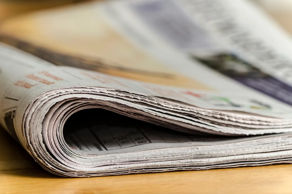 Folded newspaper on carpeted stairs showing a classified-style ad